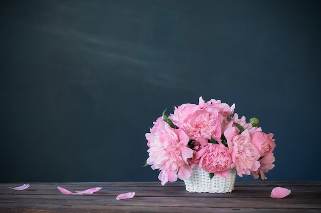 Peonia rosa in cesto su sfondo muro scuro