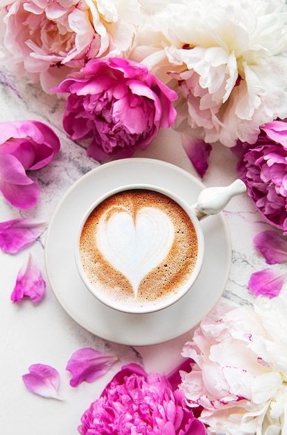 Fiori di peonia rosa e una tazza di caffè