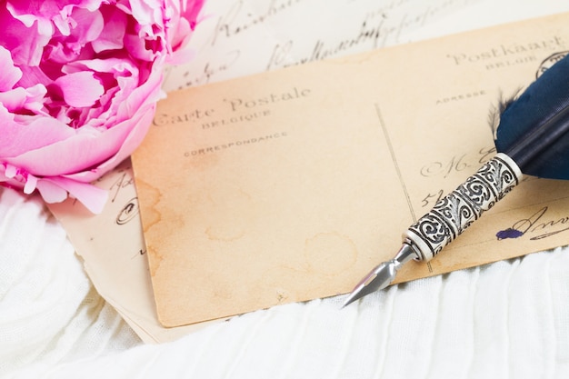 Foto peonia rosa con antica lettera vuota con copia spazio e penna piuma su pizzo bianco