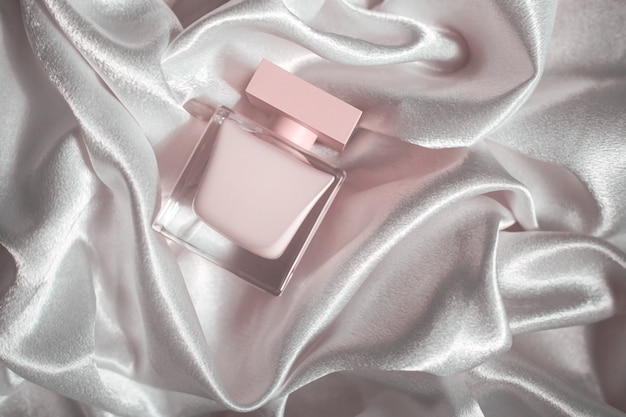 Pink perfume on a background of silk fabric