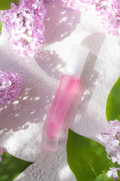 Foto bottiglia di profumo rosa e ramo lilla luce e ombra il concetto di profumi pubblicitari