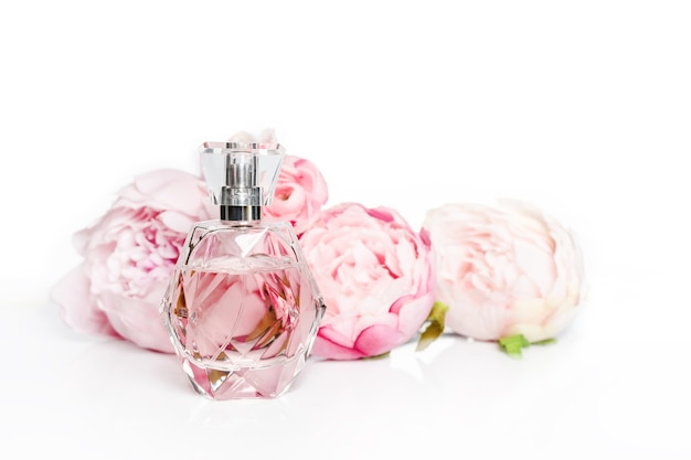 Pink perfume bottle with flowers on light surface