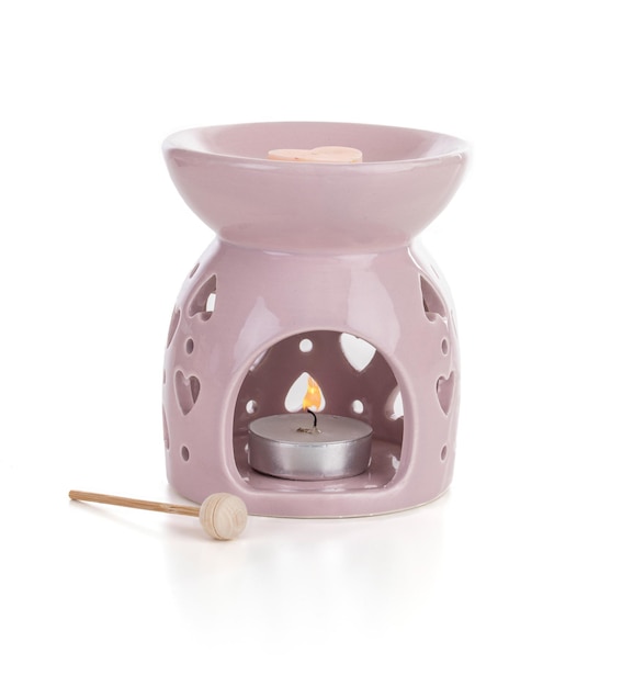 Pink perfume burner with a candle on a white background