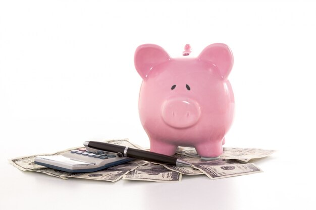 Pink piggy bank beside calculator and fountain pen