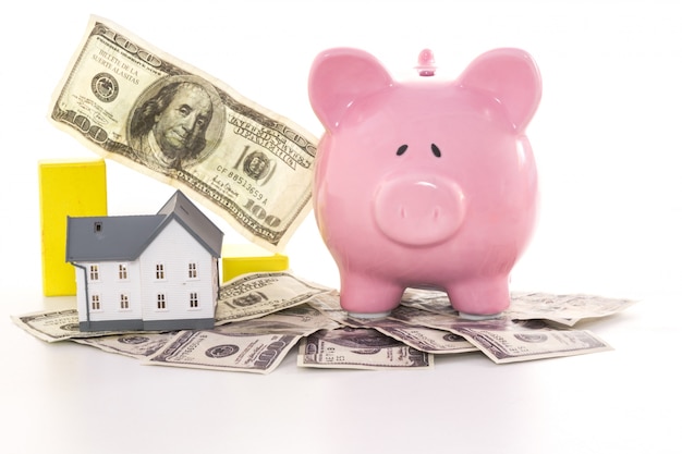 Pink piggy bank beside miniature house and graph 