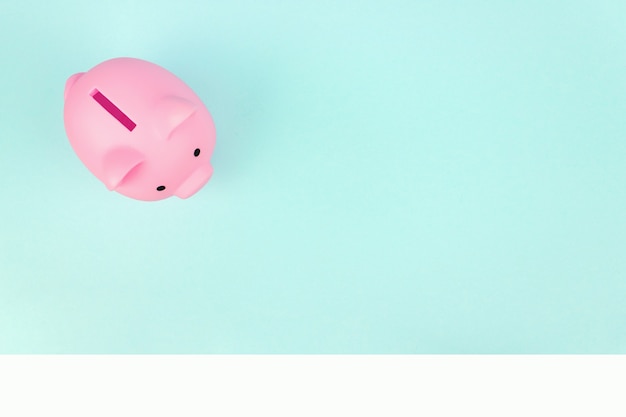 Pink piggy bank on blue background. Finance, saving money concept, financial planning of personal finances and being thrifty.