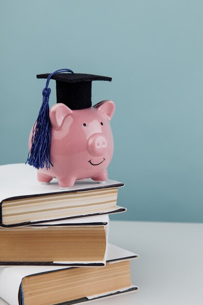 Foto salvadanaio rosa in protezione sulla pila di libri. college, laureato, concetto di educazione. immagine verticale