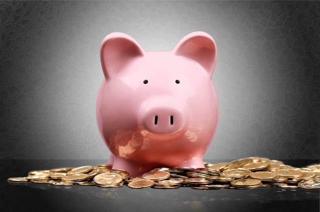 Pink piggy bank and coins on background