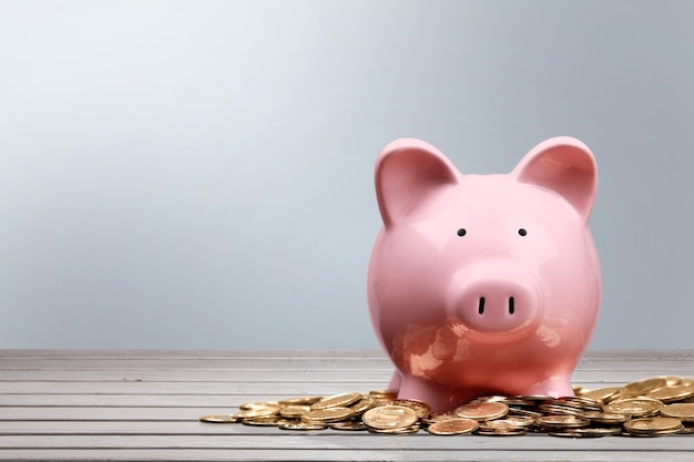 Pink piggy bank and coins on background