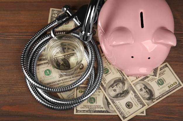 Pink piggy bank glass of water tap hose and dollars on wooden background Saving water concept