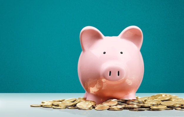 Pink piggy bank and gold coins on the desk