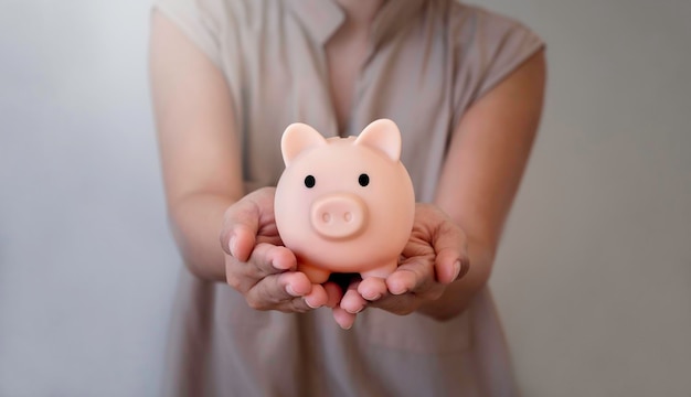 Pink piggy bank in hand The donations charity giving saving money for future growth insurance and investment concepts