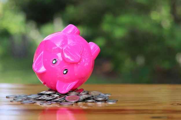 Pink Piggy Bank lies on its back in the pile of coins Thai change