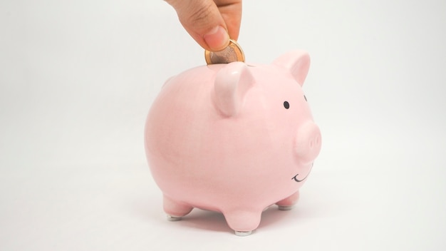 ピンクの貯金箱は白い背景にコインを節約しますコインの時間のお金とビジネスコンセプトを節約します