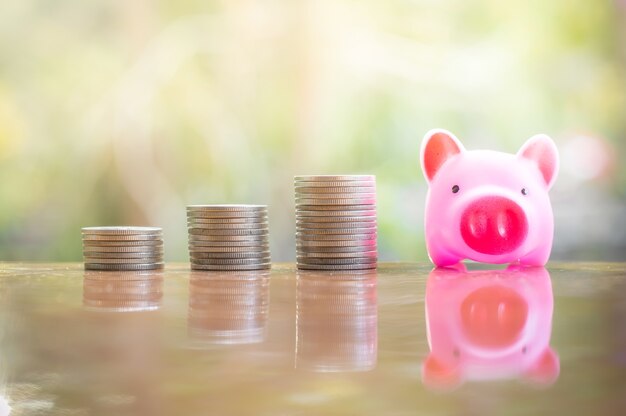 Pink piggy bank and stack of coins growing up for business investment or saving concept 