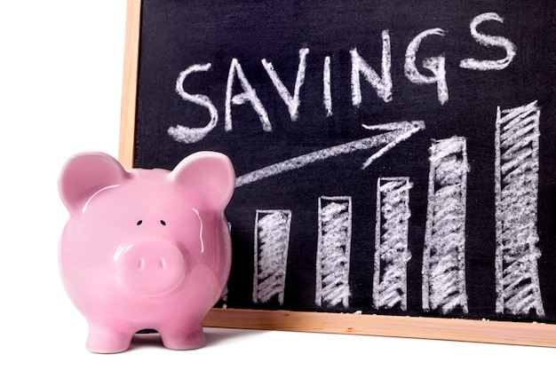 Pink piggy bank standing next to a blackboard with savings growth chart.  