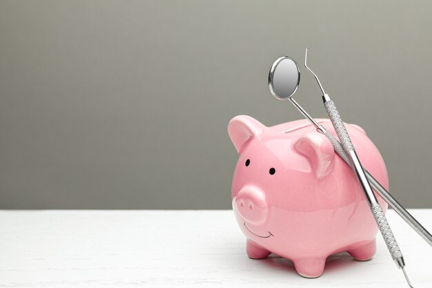 Pink piggy bank and stethoscope on a gray background Concept of how to save on health insurance