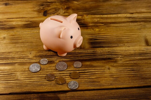 Pink piggy bank and US coins on wooden desk Saving money concept