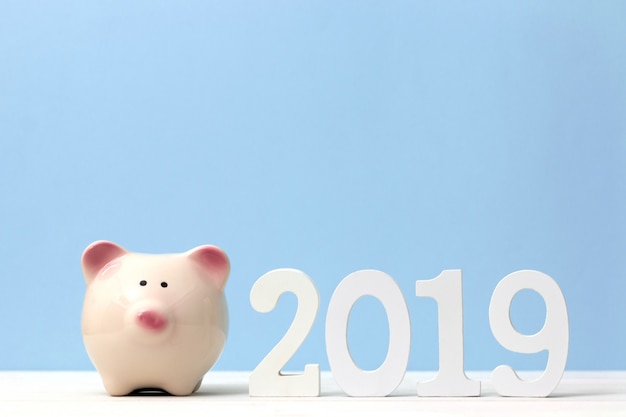 테이블에 나무 흰색 숫자 2019 핑크 돼지 저금통. 새해 복 많이 받으세요 2019