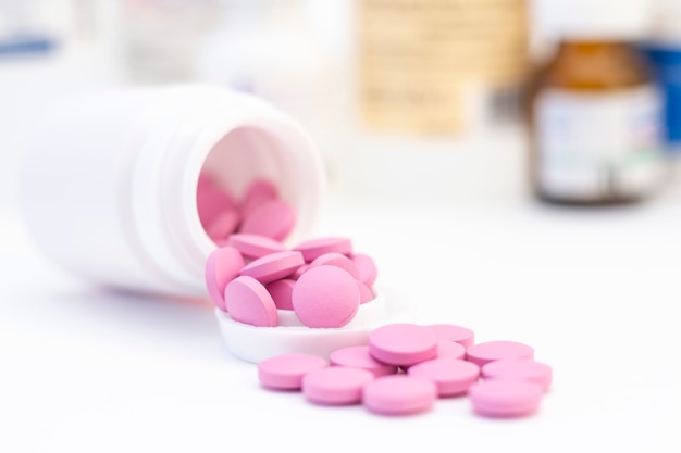 흰색 항아리에서 분홍색 알 약입니다. 건강 관리, 치료, 질병의 개념.