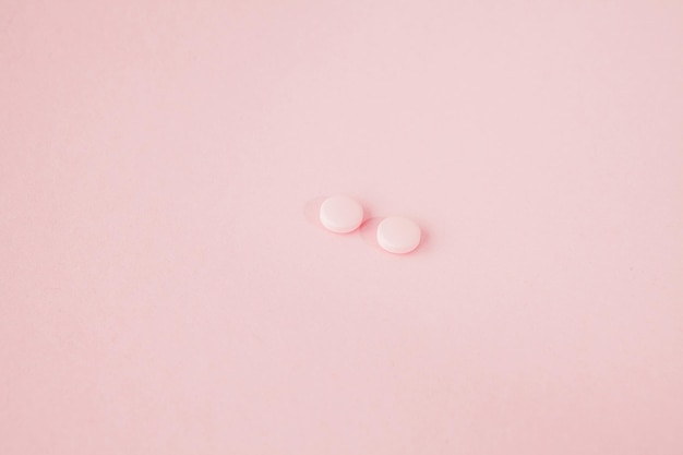 Pink pills on a pink background copy space