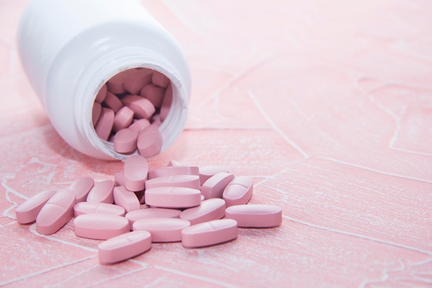 Pink pills on a pink background. Tablets in a white jar