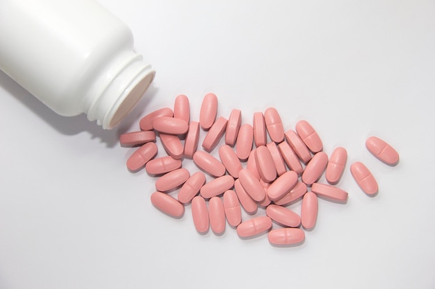 Pink pills in a white jar. Pink pills on a white background