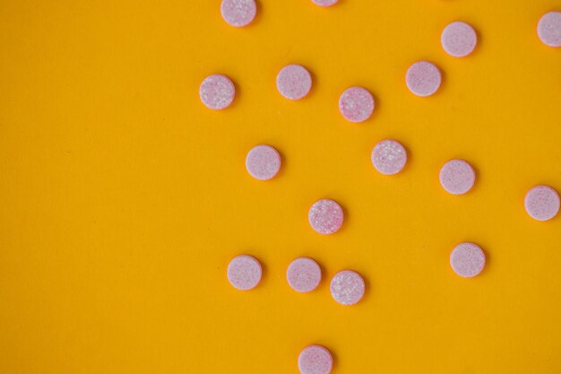 Pink pills on yellow background