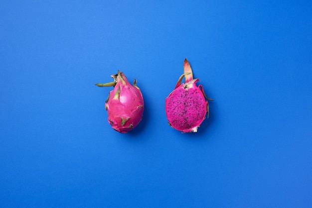 Pink pitahaya or dragon fruit on blue background Top view Copy space Creative design banner Summer time Tropical travel exotic fruit Vegan and vegetarian concept