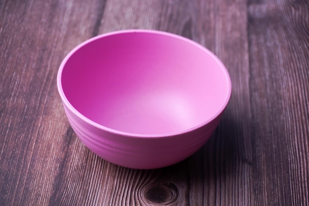 Pink plastic bowl on wooden background