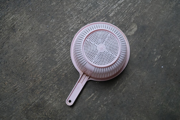 A pink plastic brush sits on a wooden surface.