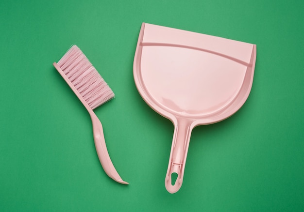 Pink plastic scoop and brush on a green surface