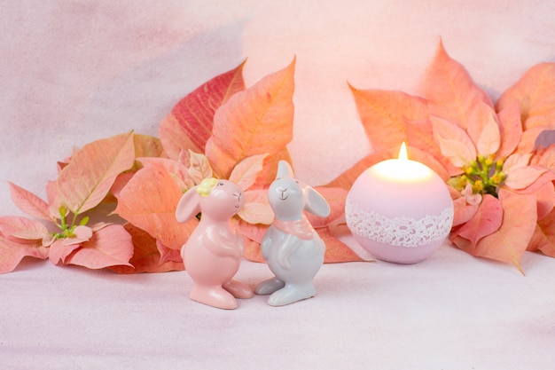 pink poinsettia, two figures of rabbits and a candle