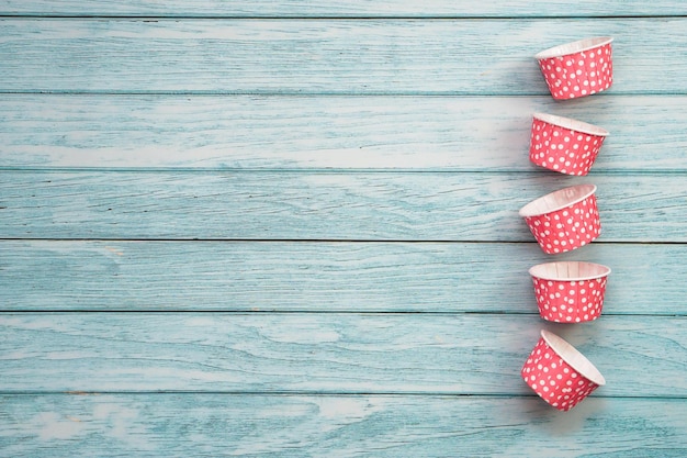 Pink polka dot cupcake cases on blue wooden floor Material for baking