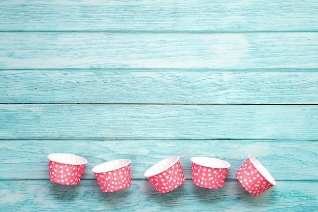 Pink polka dot cupcake cases on blue wooden floor Material for baking