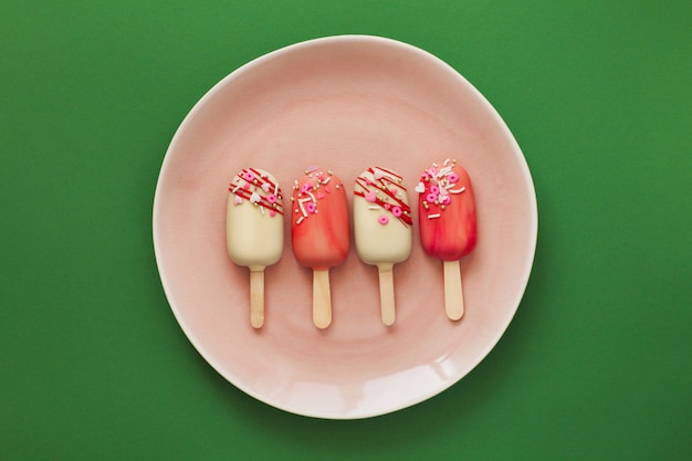 Pink popsicle cakes on a green background