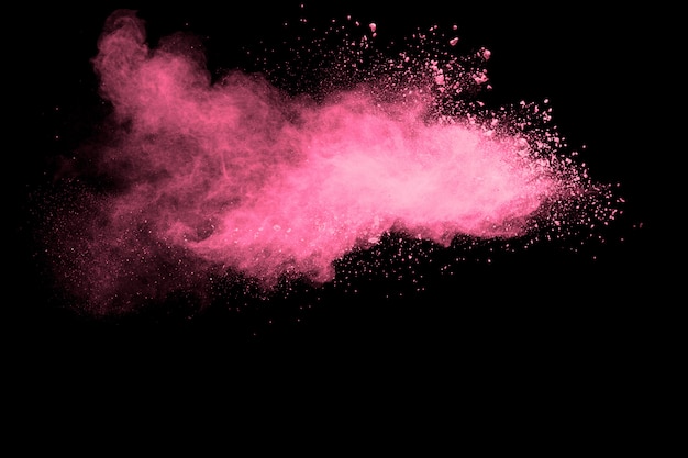 Photo pink powder explosion on black background.pink dust splash cloud on dark background.