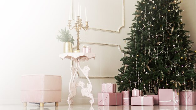 写真 白いインテリアのクラシックなアパートメントのクリスマスツリーの下にリボンが付いたピンクのプレゼントボックス