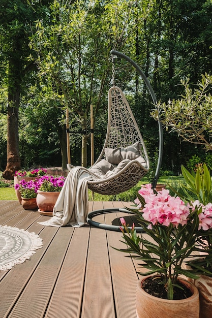 Photo pink and purple flowers in green garden with fancy swing egg chair