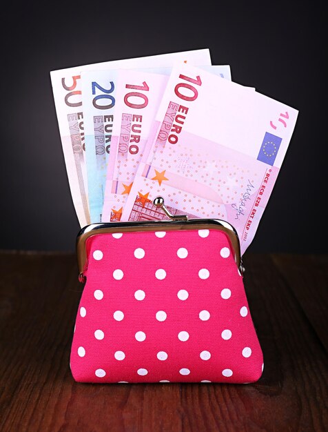 Photo pink purse with money on table on black background