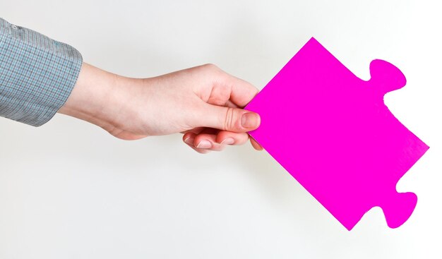 Photo pink puzzle piece in female hand