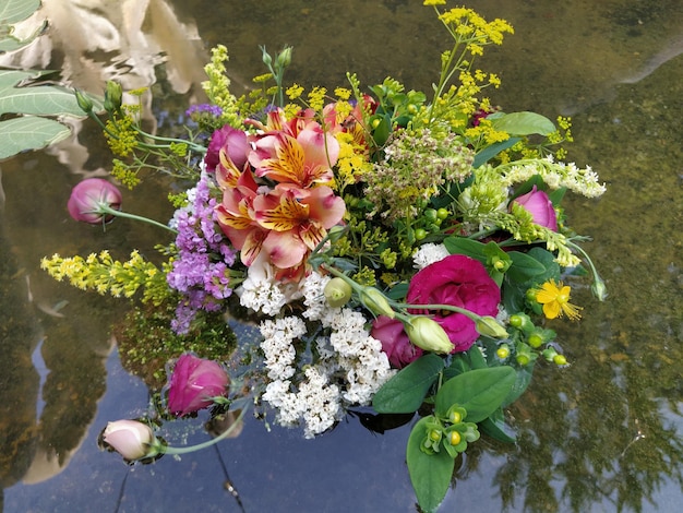 연못 물에 떠 있는 꽃다발에 분홍색과 빨간 장미 여름 휴가 Ivan Kupala 여름 하지 추수 축제를 위한 장식으로 뽑은 꽃봉오리