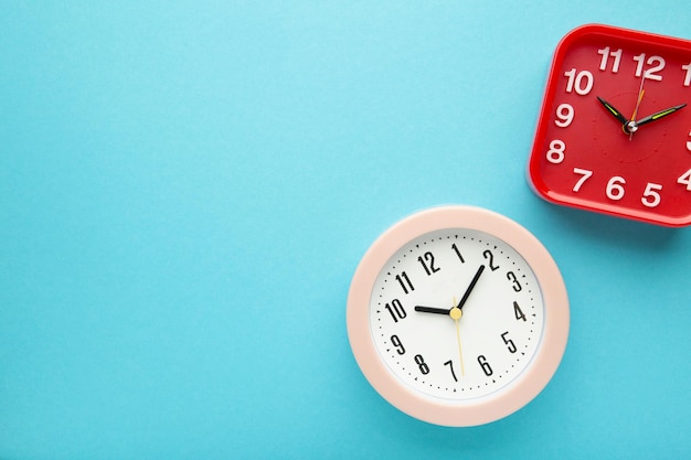 Pink and red wall clock on blue background Vertical photo