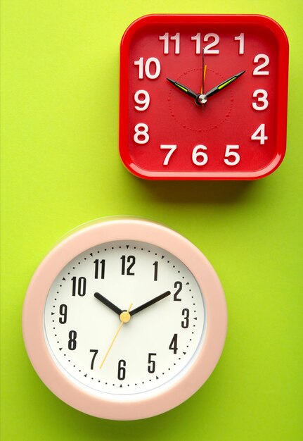 Pink and red wall clock on green background Vertical photo