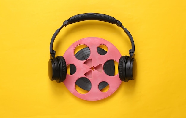 Pink retro audio reel with headphones on yellow background\
minimalism music concept top view