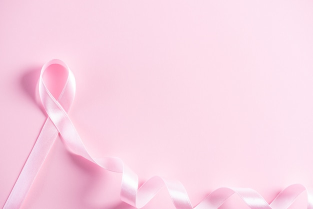 Pink ribbon on pink paper background for supporting breast\
cancer awareness