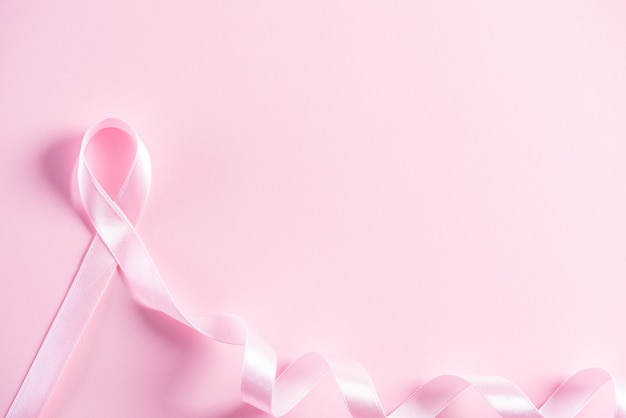 Nastro rosa su sfondo di carta rosa per sostenere la consapevolezza del cancro al seno