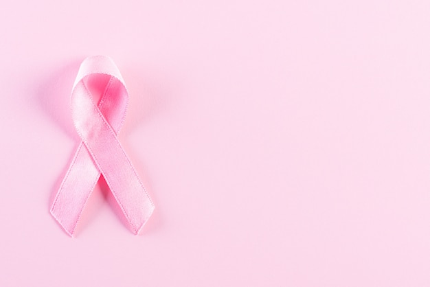 Pink ribbon on pink pastel background for breast cancer awareness month campaign.