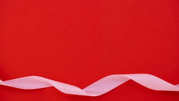 Pink ribbon on red background with copy space