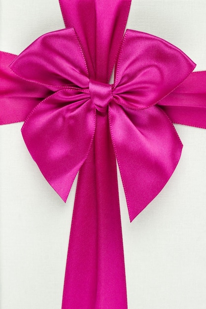 Pink ribbon with bow as gift on white background